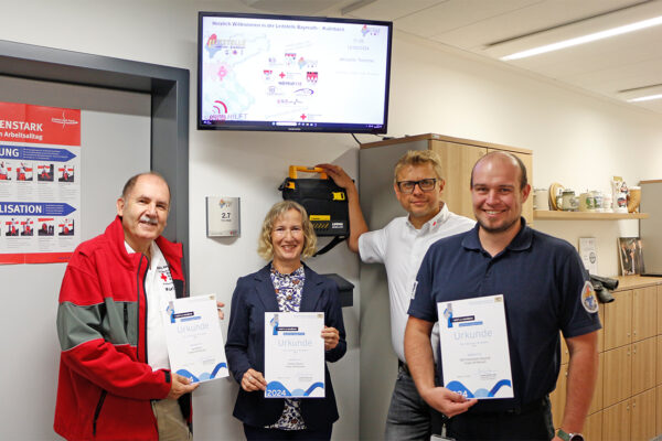 Zu sehen: Karl Bernet (l.) mit Chrsitine Bernet, Markus Ruckdeschel (BRK-Kreisgeschäftsführer Bayreuth) und Dr. Christopher Häfner (Leiter der ILS Bayreuth/Kulmbach) mit den Auszeichnungs-Ukunden des Bayerischen Staatsministeriums des Innern für den Bayerischen Engagiert Preis 2024.